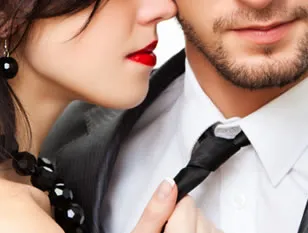A woman pulling a man close by his tie, faces near